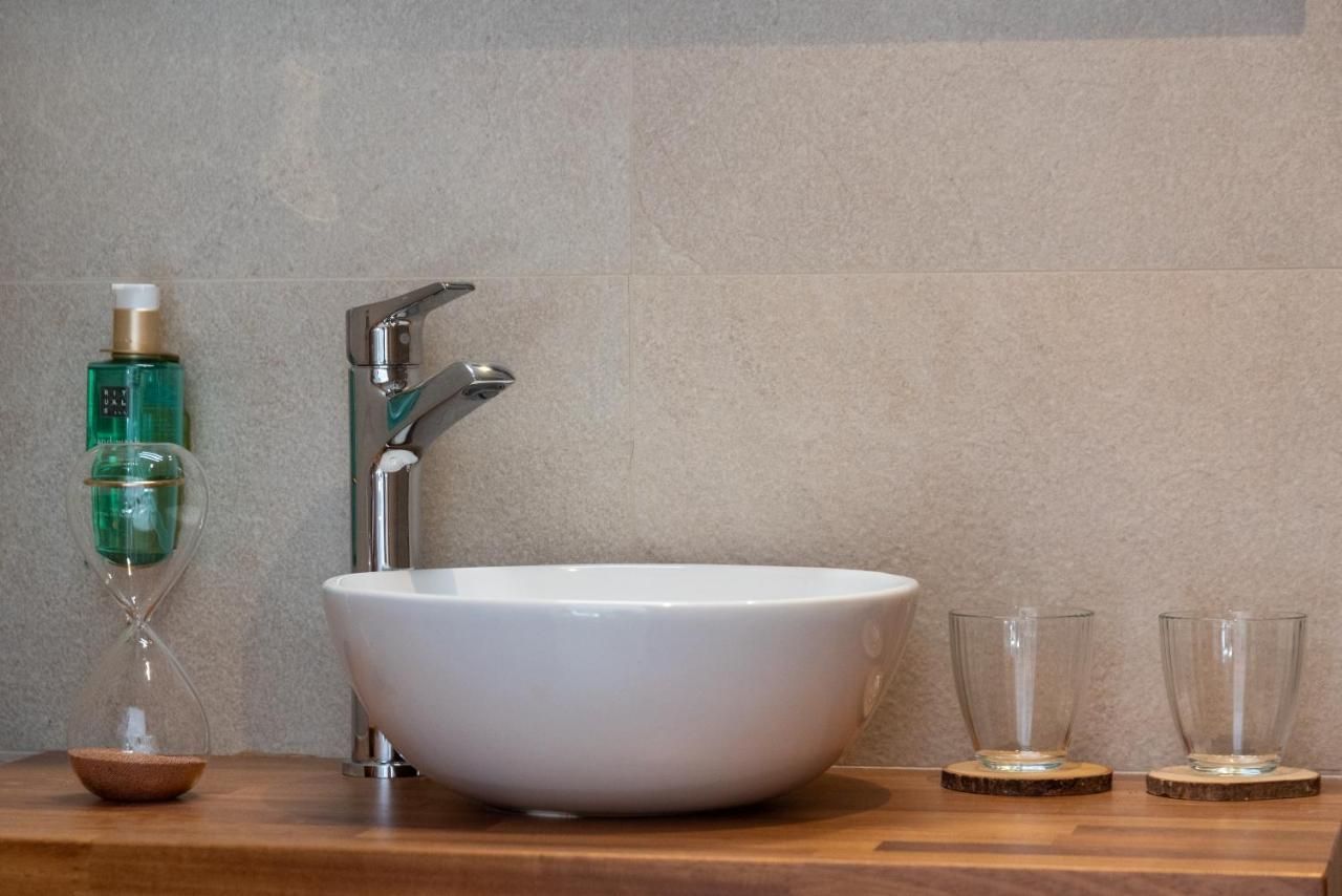 Un lavabo de baño está sobre un mostrador de madera al lado de un reloj de arena.