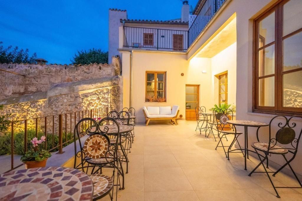 Patio exterior con mesas y sillas, un sofá y vistas a un edificio al atardecer.